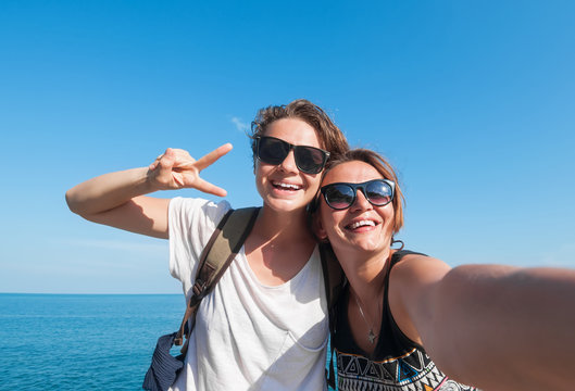 Two beautiful young women making selfie on the beach
