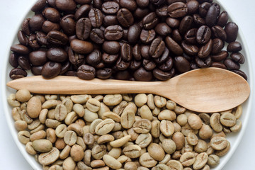 Raw and roasted coffee beans with wooden spoon.