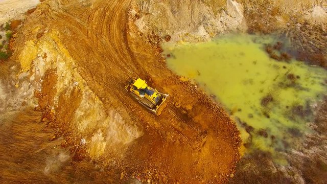 Aerial view of bulldozer on muddy construction site or dump. Heavy industry from above. Industrial background from devastated landscape.