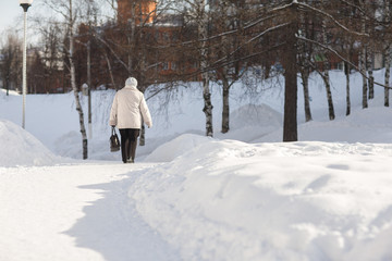 Fototapeta na wymiar Older woman walking on a snowy road