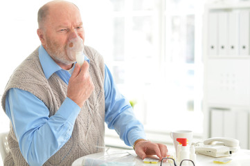 Sick elderly man makes inhalation