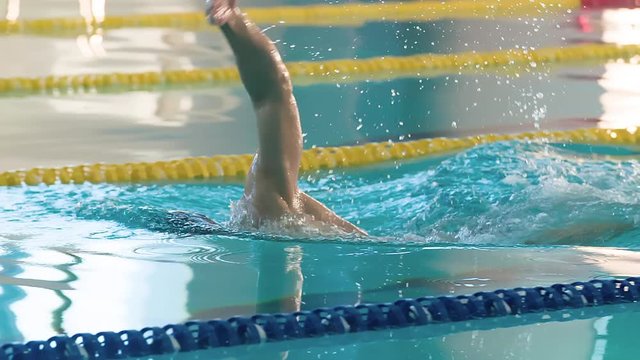 Male swimmer swims in pool HD slow-motion video. Front crawl freestyle training of professional man athlete. Water splashing of arms stroke. Side view