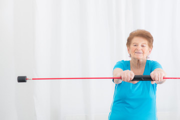 seniorin macht fitnessübung mit dem gymnastikstab