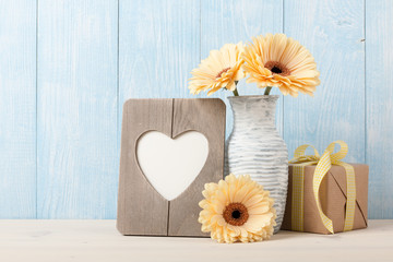 Fresh yellow gerbera flowers, gift box and heart shaped photo frame