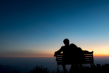 Fototapeta na wymiar silhouette of Couple sit and embrace in the Sunset Background with copy space
