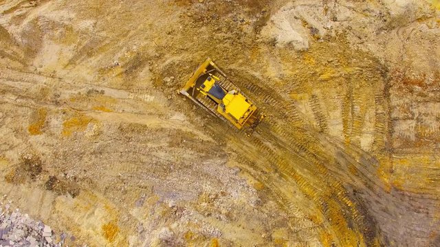 Aerial view of bulldozer on muddy construction site or dump. Heavy industry from above. Industrial background from devastated landscape.