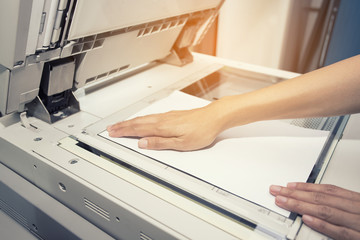 woman hands putting a sheet of paper into a copying device