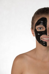 Happy beautiful girl with acne on a white background in a cosmetic mask black