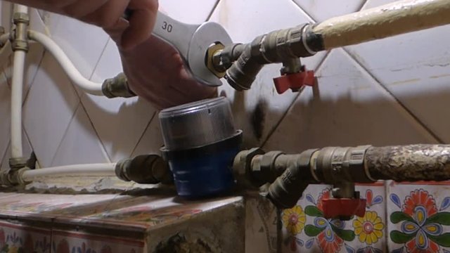 Plumber spanner unscrews the nut on the water pipe