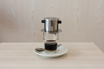 Traditional style Vietnamese coffee dripping in to a glass below with soft background and depth of...