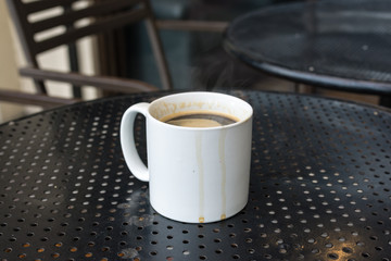 Americano coffee in standard white mug on black metal table with coffee runs