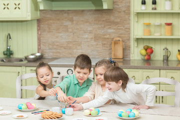 Obraz premium Easter day. A group of children paint Easter eggs and laugh.