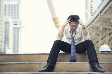 Obraz premium Young depressed businessman sitting on the stairs