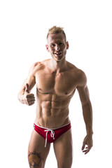 Fototapeta premium Muscular man shirtless doing thumb up sign for OK, smiling at camera, isolated on white