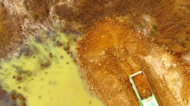 Aerial view of truck riding on muddy road trough a dump. Heavy industry from above. Industrial footage from devastated landscape. 