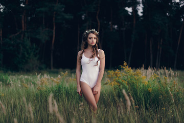 Girl model in white bodysuit laying on green grass. Top view
