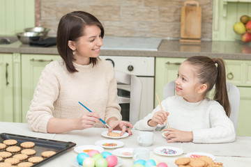 Mom and her daughter baking together and decorating the cookies