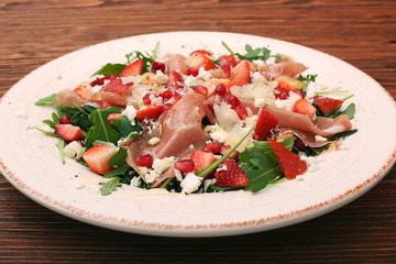 Arugula salad with strawberries, feta cheese, prosciutto, parmes