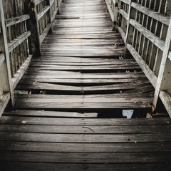 Old and broken  wooden bridge path across the lake/river,  selective focus