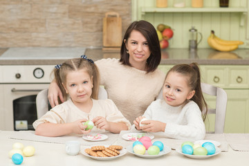 Obraz na płótnie Canvas little sisters with mom playing with Easter eggs on Easter day