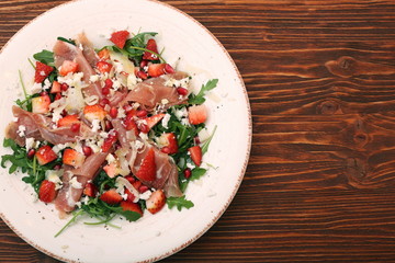 Arugula salad with strawberries, feta cheese, prosciutto, parmes