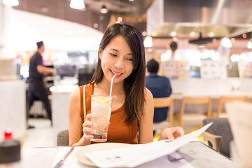 Woman picking dish in menu at restaurant