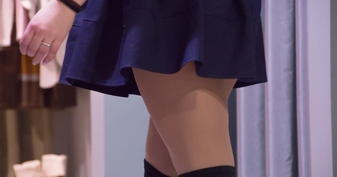 Girl trying on dress on shopping clothes store HD video. Young woman spinning in shop fitting room at mall boutique