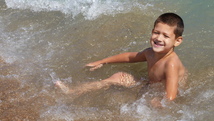 Fototapeta premium Little boy plays in the sea