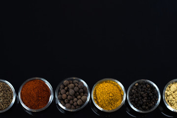 bowls of various dip sauces on black background, top view
