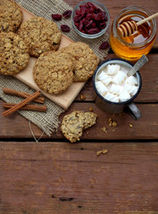 Flourless gluten free peanut butter, oatmeal, honey, dried fruits cookies and cup of cocoa with marshmallows on wooden background. Vertical. Copy space