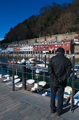 Paesi Baschi, Spagna, 28/01/2017: un uomo con il basco, di spalle, nel porto guarda lo skyline della città vecchia di Donostia San Sebastian, la città costiera sul Golfo di Biscaglia