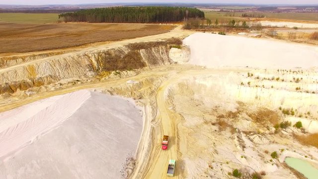 Aerial view of truck riding on muddy road trough a dump. Heavy industry from above. Industrial footage from devastated landscape. 
