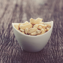 raw cashew nuts in white ceramic bowl on wood table