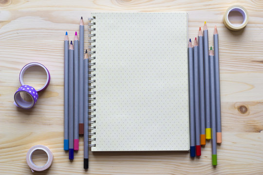 Notepad for creativity and ideas with colored pencils on the wooden background