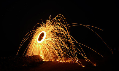 Firework showers of hot glowing sparks from spinning steel wool on the ground. Light painting (Long Exposure)