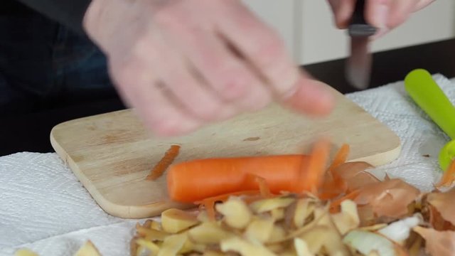 Mann schält und schneidet Karotten