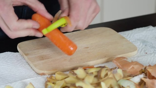 Mann sch&auml;lt und schneidet Karotten