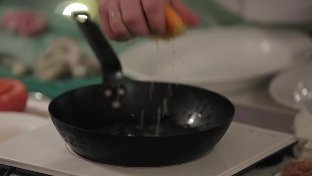 Cook cooking on a kitchen with frying pan