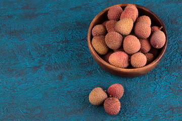 Lychee in a wooden bowl on a blue cement background