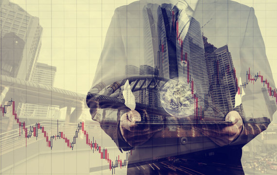 Double exposure of success businessman using digital tablet with city landscape background.with stock chart, investment concept. with the small world (Elements of this image furnished by NASA)