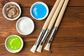 Brush and colorful paint in jars on an old wooden background with copy space