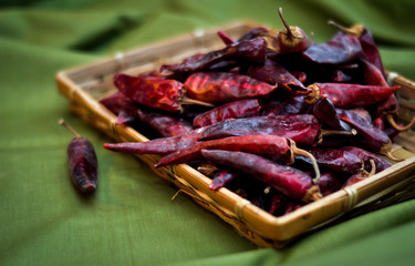 Dried red hot chili peppers are lying in a heap, glitering with different shades of red