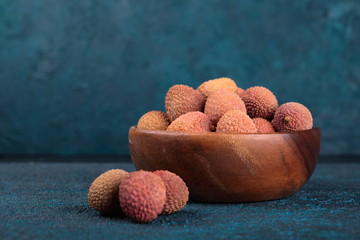 Lychee in a wooden bowl on a blue cement background