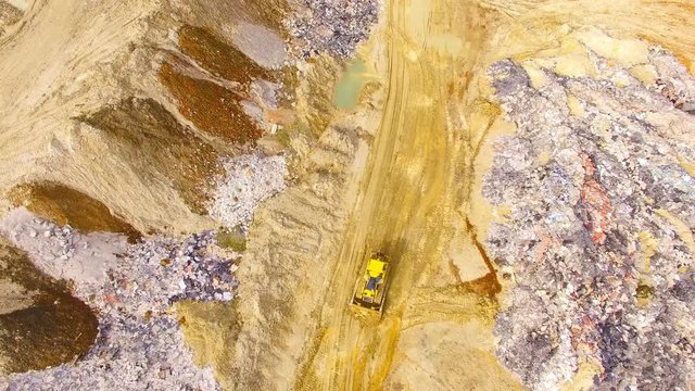 Aerial view of bulldozer on muddy construction site or dump. Heavy industry from above. Industrial background from devastated landscape.