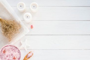 Spa composition with candles, sea salt and flowers on white wooden background. Flat lay.