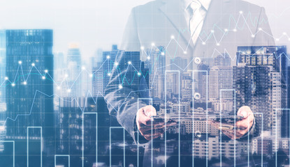 Fototapeta na wymiar Double exposure of businessman using digital tablet with city landscape blurred background.Forex graph on the business background