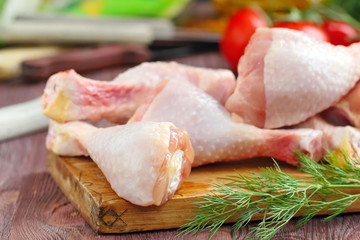 Raw chicken legs with spices and vegetables on a cutting board