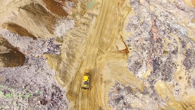 Aerial view of bulldozer on muddy construction site or dump. Heavy industry from above. Industrial background from devastated landscape.
