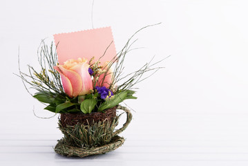 Bouquet of pink roses on white wooden table with empty card