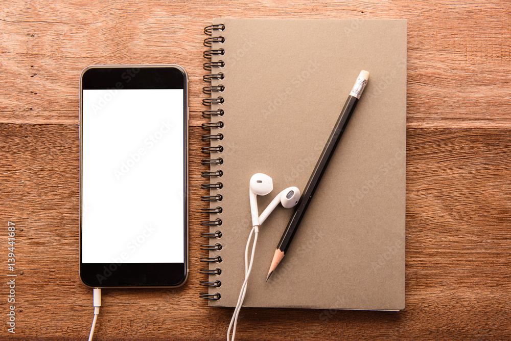 Aufkleber Smartphone with white screen and Note book On Wooden Table With Copyspace